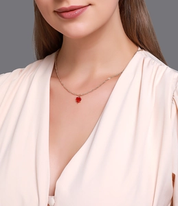 Gros plan d'une chaîne dorée élégante avec pendentif cœur rouge en cristal sur un mannequin