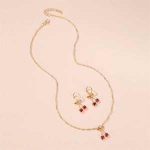 Détail d'un ensemble collier et boucles d'oreilles cerises dorées avec cristaux rouges