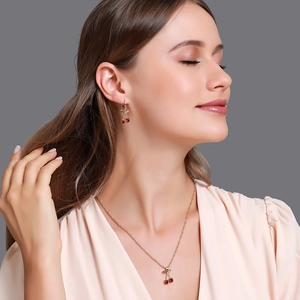 Détail d'un ensemble collier et boucles d'oreilles cerise avec cristaux rouges sur modèle