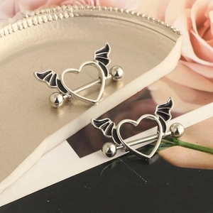 Silver winged heart nipple rings set on a decorative plate with pink roses