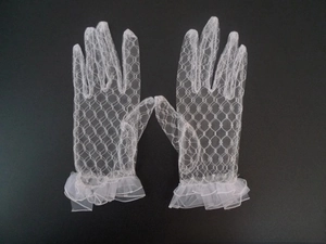 Detail of white lace gloves featuring elegant double-layered ruffled cuffs and mesh texture