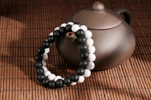 Close-up of matte black and white turquoise bead bracelets on ceramic teapot