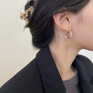 Close-up of elegant silver geometric triangular earrings and a tortoiseshell hair claw clip