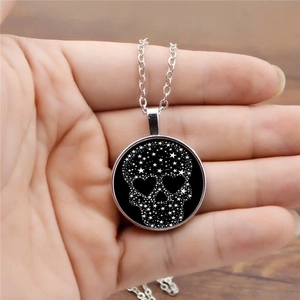 Silver necklace with a round black skull pendant featuring white star and heart details