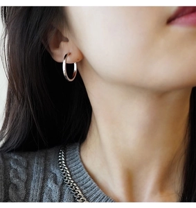 Primo piano di orecchini a cerchio in argento e collana a catena coordinata da donna
