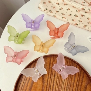 Flat lay of colorful matte oversized bow hair clips on a wooden tray with a floral cloth