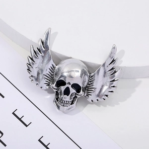 Detailed view of a vintage silver winged skull brooch with gothic punk style carvings