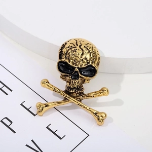 Macro view of vintage gold skull and crossbones brooch with black enamel eye details