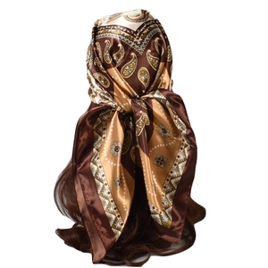 Brown and gold paisley silk scarf styled on a mannequin head with geometric patterns