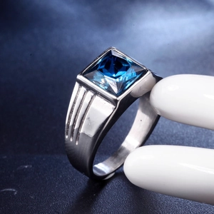 Detailed view of silver titanium steel ring with a blue gemstone on a white hand model