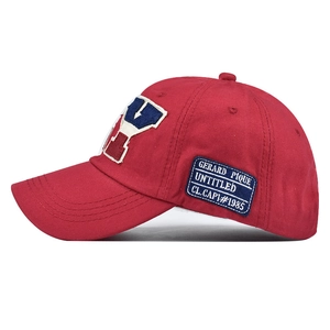 Detail of red cotton baseball cap featuring side embroidery patch and woven label detail
