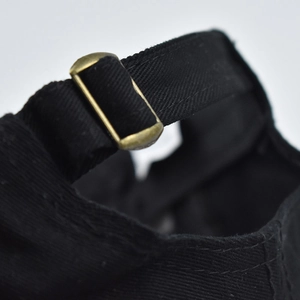 Close-up of black cotton baseball cap back with antique bronze metal adjustment buckle