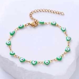 Detail of gold chain bracelet with eleven green heart-shaped evil eye charms on a stone base