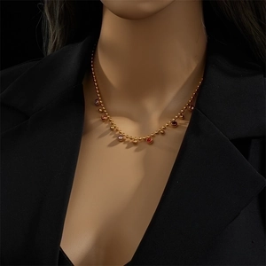 Gold beaded ball chain necklace with multi-colored gemstone pendants on a model