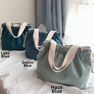 Detail of drawstring canvas handbags in lake blue, denim blue, and haze blue tones