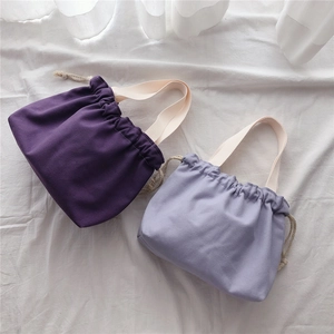 Detail of solid canvas tote bag showing drawstring closure and durable woven handles