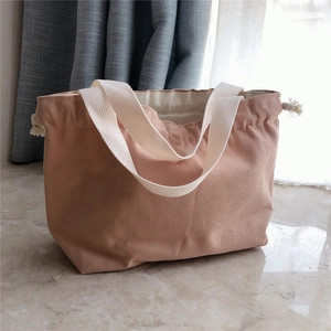 Detail of pink canvas handbag with cream strap handles and drawstring closure