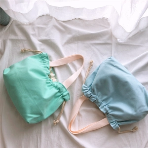 Detailed close-up of mint green and light blue drawstring canvas handbags with textured fabric