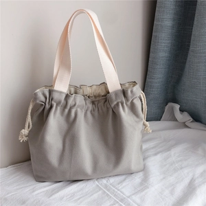 Detail of gray canvas drawstring tote bag with thick off-white woven handles and side knots