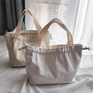 Detail of minimalist canvas tote bags showing drawstring closure and wide strap texture