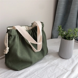 Detailed view of dark green canvas tote bag with drawstring closure and cream handles