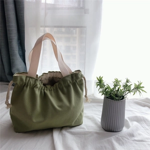 Detailed view of dark green drawstring canvas bag with off-white cotton handles and lining