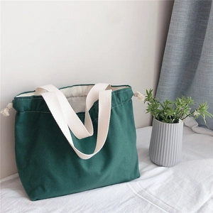 Detail of dark green canvas tote bag with cream straps and drawstring closure