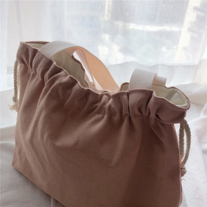 Detailed texture of dusty rose canvas tote bag with cotton drawstring and white strap