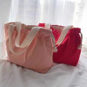 Detail view of pink and red canvas drawstring bags with thick cotton straps and white handles
