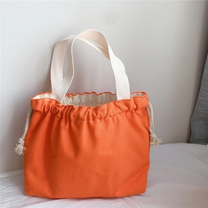 Close-up of bright orange canvas drawstring tote bag showing thick woven texture