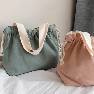 Detail view of thickened canvas tote bag showing drawstring closure and wide cream strap