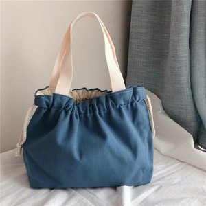 Detailed texture of thick navy canvas bag with cream woven handles and drawstring
