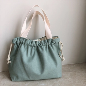 Detailed texture of thick sage green canvas handbag with drawstring and woven handles