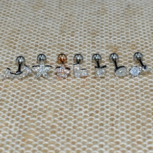 Close-up of stainless steel stud earrings set with crystal moon, star, and flower shapes