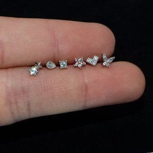 Detailed close-up of micro-inlaid zircon stud earrings set on finger for size reference