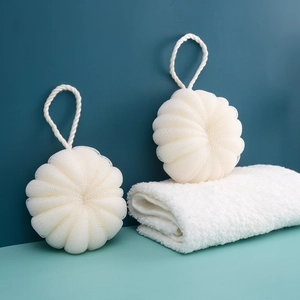 Close-up of two white mesh bath sponges with hanging ropes against a blue background