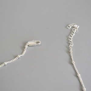 Dettaglio della chiusura a moschettone in argento e catena di estensione con perle