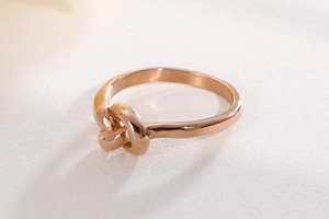 Close-up of minimalist rose gold knot ring featuring a delicate polished knotted design