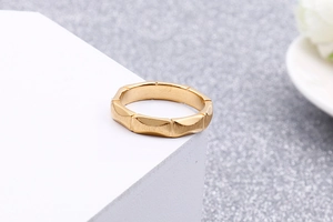 Detail of matte gold geometric rhombus ring with brushed texture on a white stand
