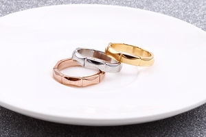 Detailed view of stacked bamboo-style rings in rose gold, silver, and gold on white ceramic