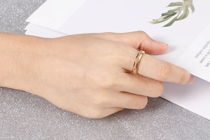 Detail of rose gold geometric ring with polished trapezoid facets on a female hand