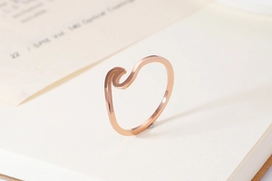 Detailed close-up of rose gold wave ring on book, minimalist geometric jewelry for women