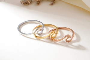 Detail of matte wave rings in silver, gold, and rose gold with brushed metal texture