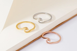 Detailed view of wave-shaped stainless steel rings in gold, silver, and rose gold