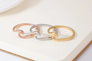 Detailed view of wave rings in rose gold, silver, and gold finishes on a notepad