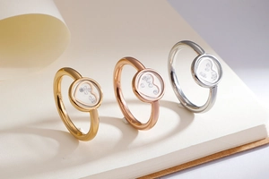Three heart-shaped rings in gold, rose gold and silver with floating stones on a notebook