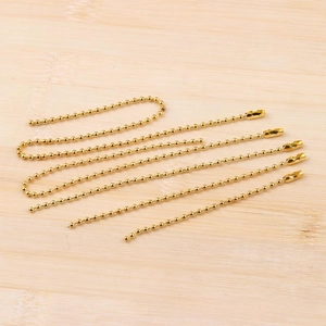 Detail of 3.2mm golden ball chains with metal connectors on light wood background