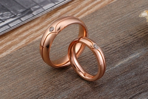 Detail of rose gold couples ring set with round diamonds on elegant wooden background