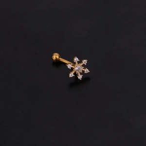 Detail of gold curved barbell piercing featuring a sparkling crystal snowflake charm