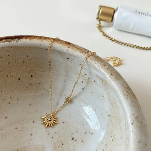 Macro view of gold sunburst pendant with zircon pavé and delicate star charm detail